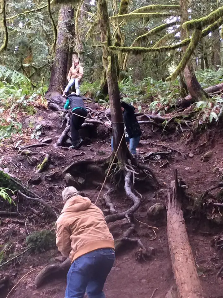 Hikers climb the side of a waterfall with the aid of a rope in this Oregon travel guide.
