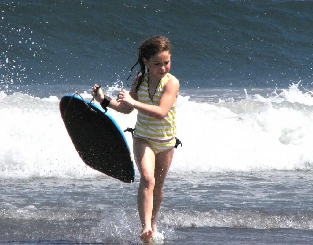 Young girl carrying a boogie board out of the surf
