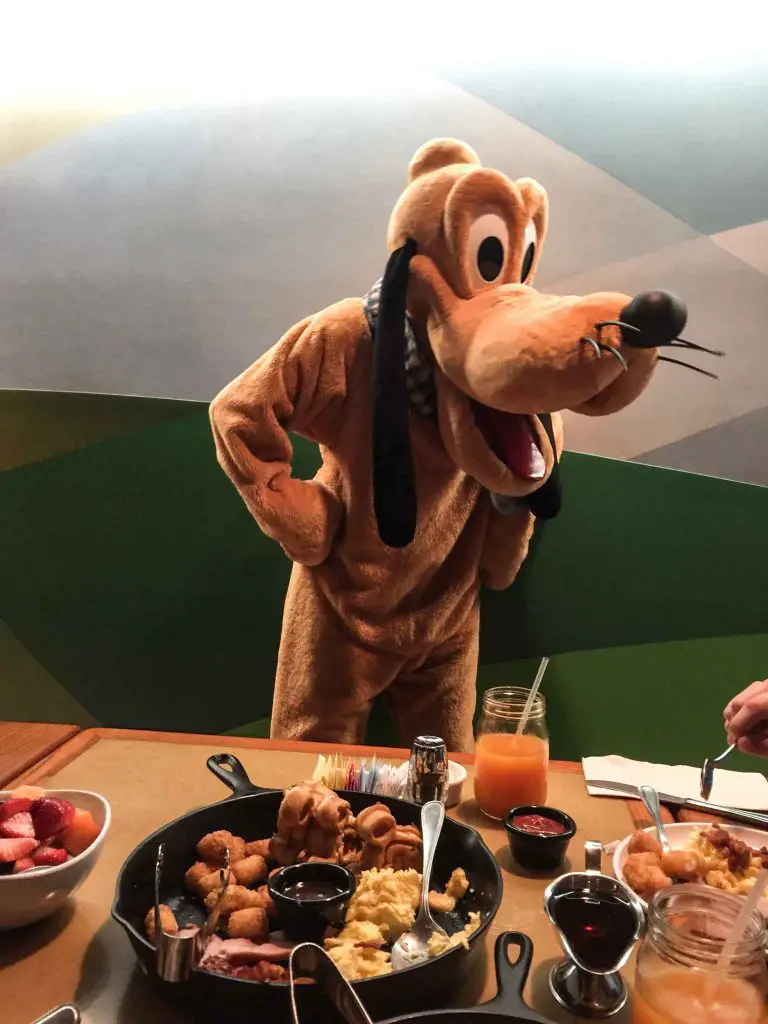 Pluto visits a family during breakfast at a character meal included in the Disney Dining plan.