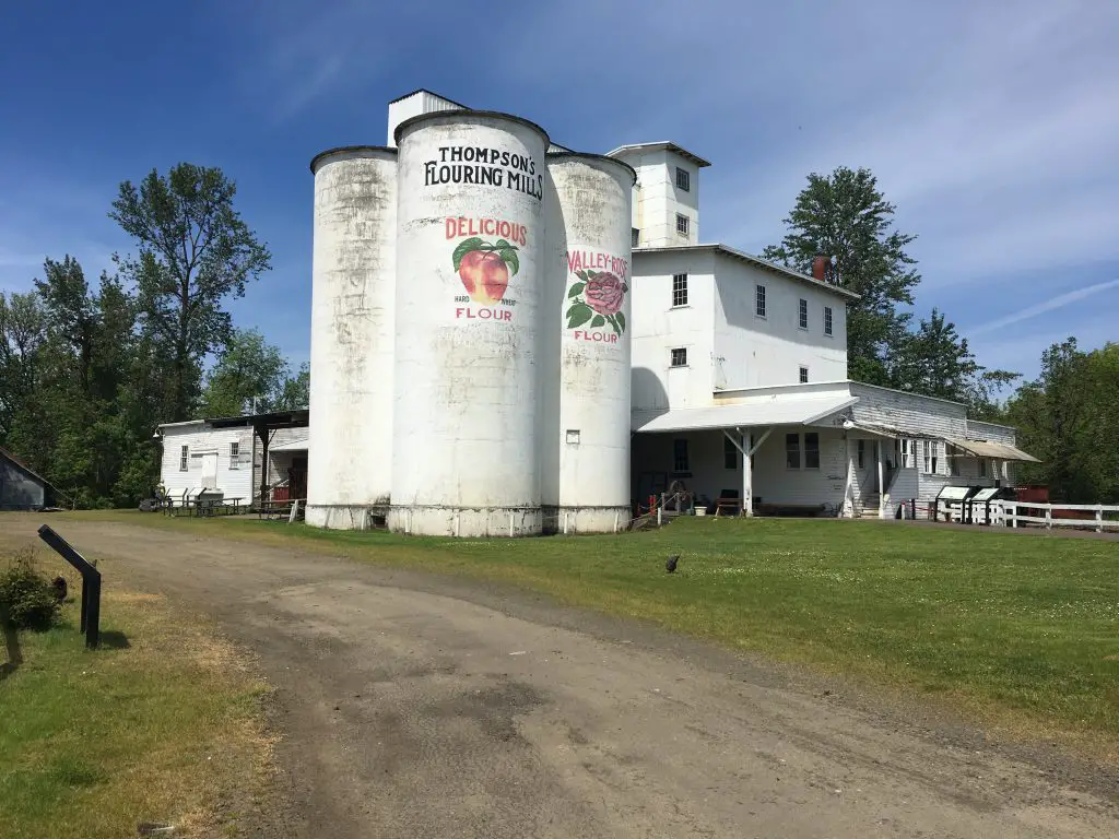 Thompson Mills with white silos and green grass is a historic Oregon destination