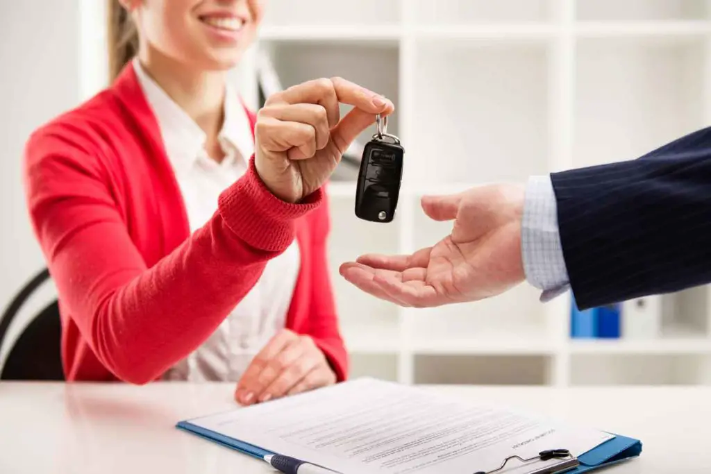 Car rental agent handing traveler a  vehicle key