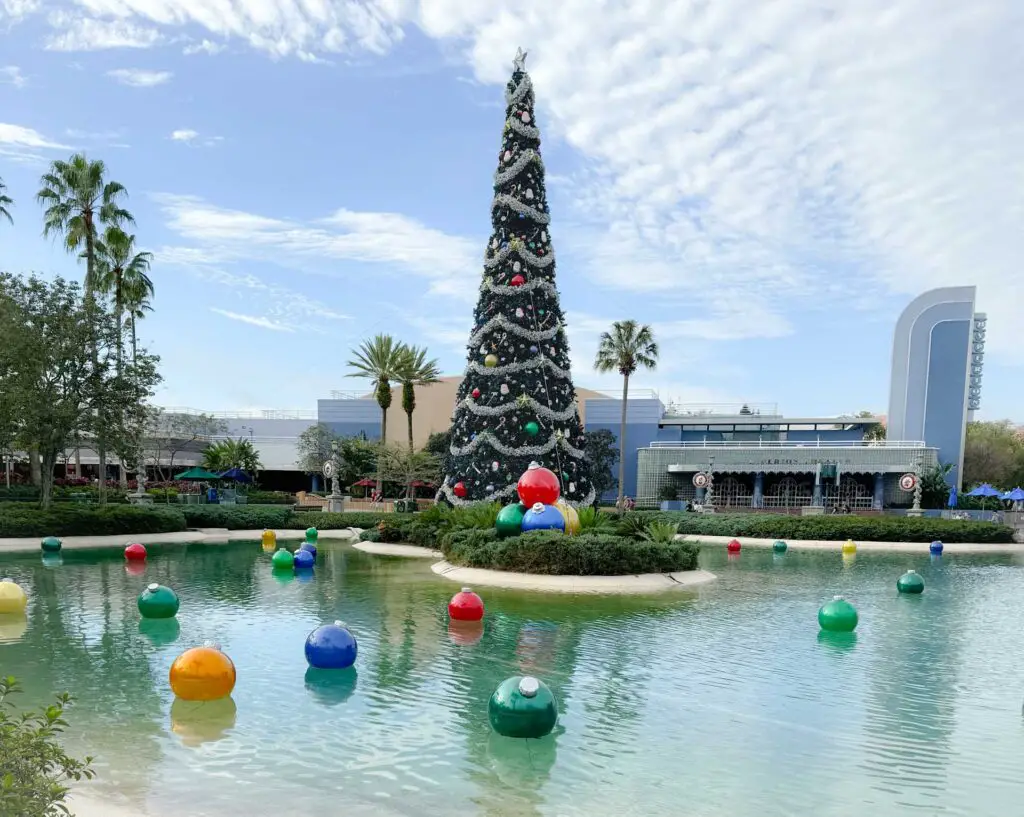 a large christmas tree with lights and ornaments in a pond