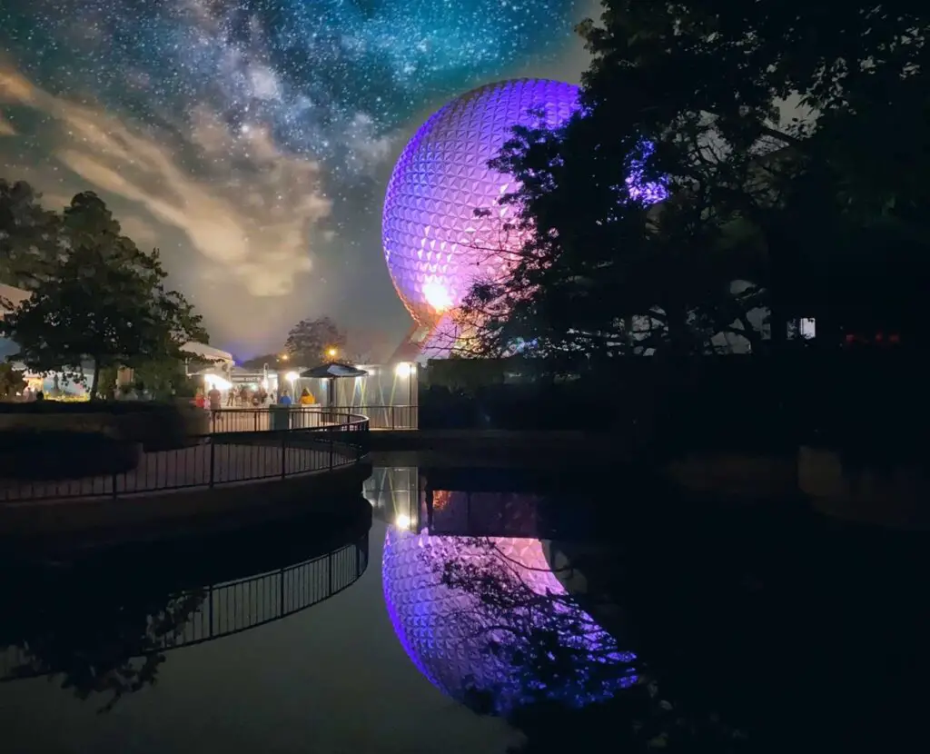 Epcot's Spaceship Earth lit in purple and reflected in water
