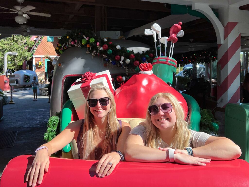 Two young women pose for a picture inside Santa's sleigh at the Winterland Golf Course, an excellent thing to do outside the parks.