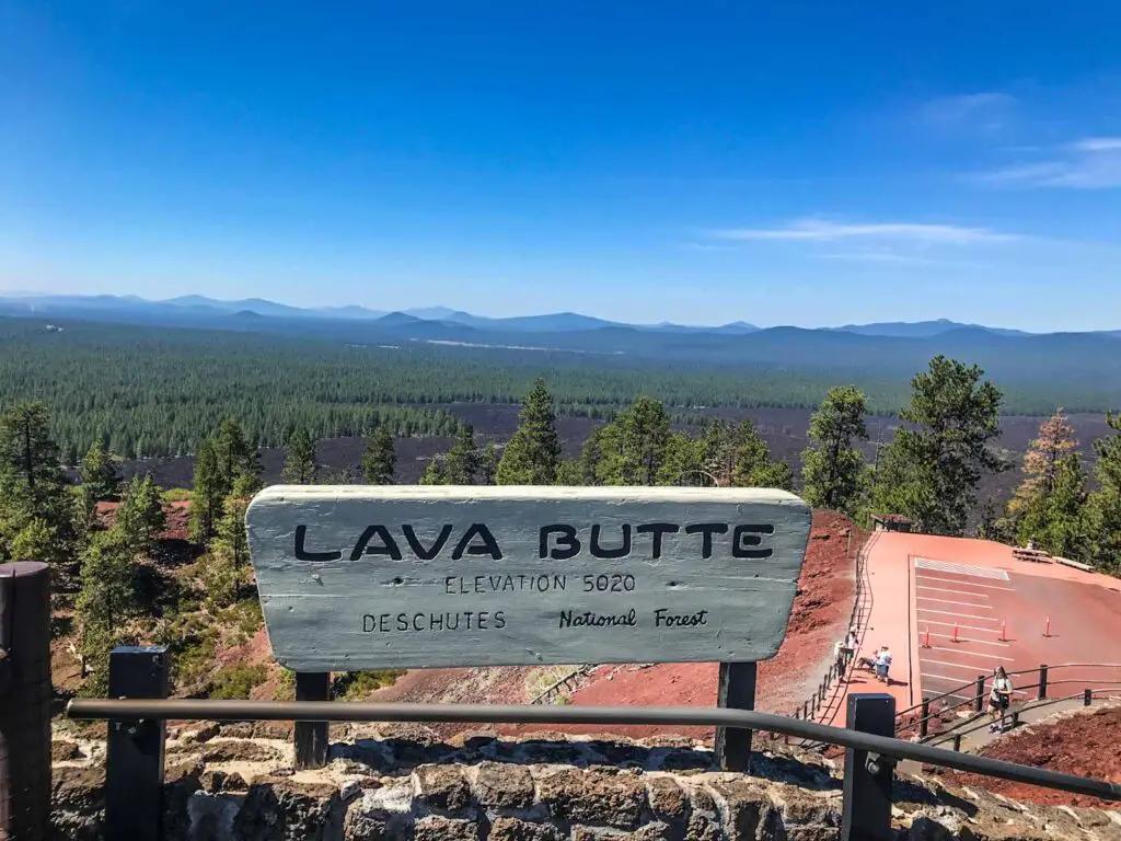 Lava Butte Sign atop Lava Butte Cinder Cone, Newberry Volcanic Monument, with an expansive field of pines in the background.