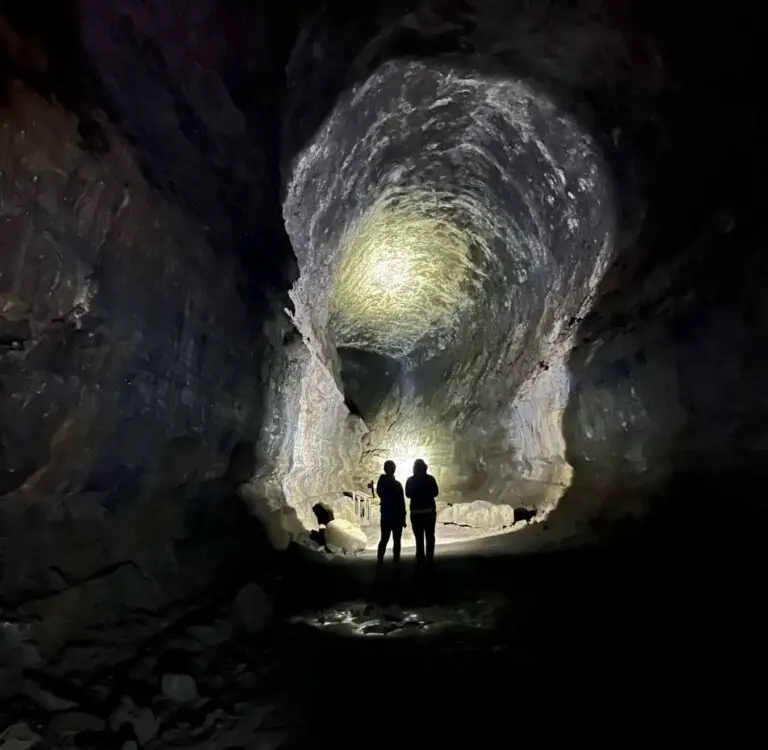 two women in shadow inside a lava tube cave in central Oregon