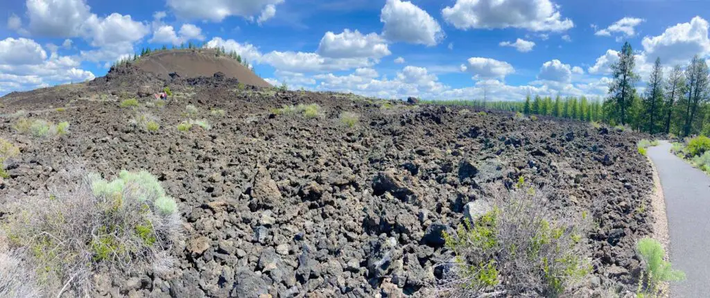 A trail leads off through the Newberry Volcanic Monument lava flows with the extinct caldera in the background