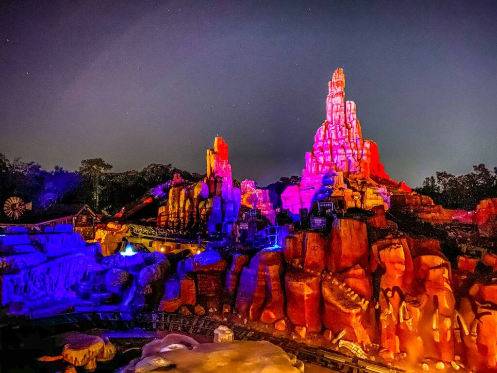 Big Thunder Mountain ride lit up in pinks and blues during the night at Magic Kingdom.