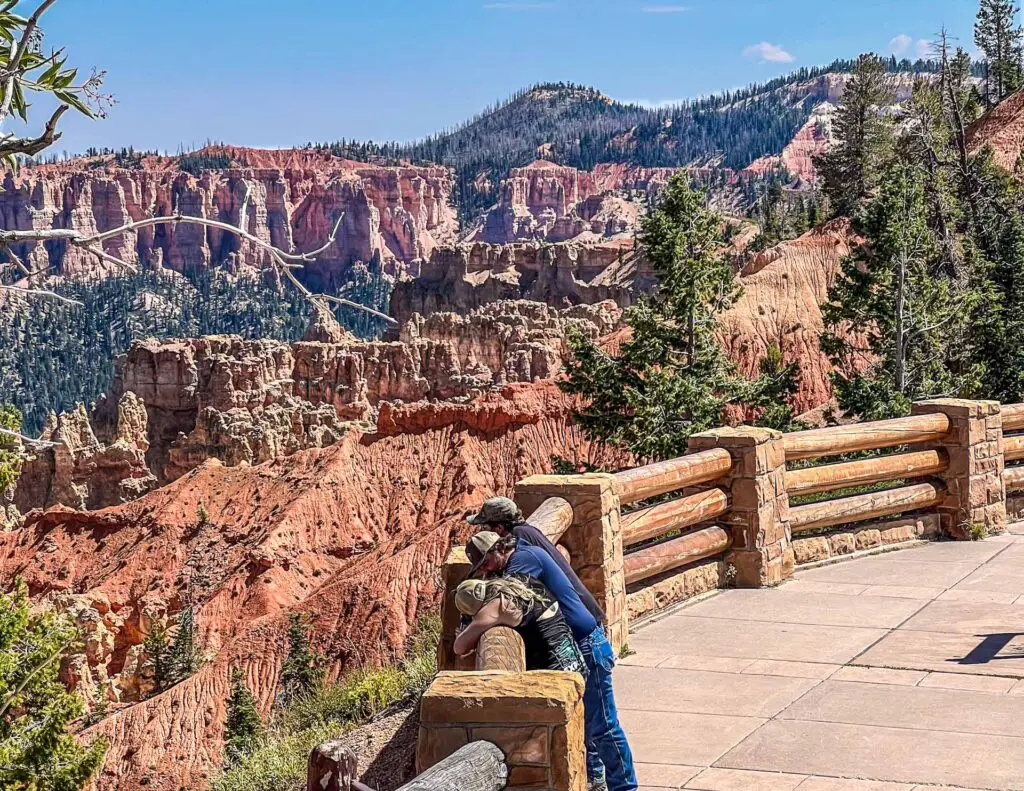A man and a woman peer over a fence into Ponderosa Point at Bryce Canyon Park