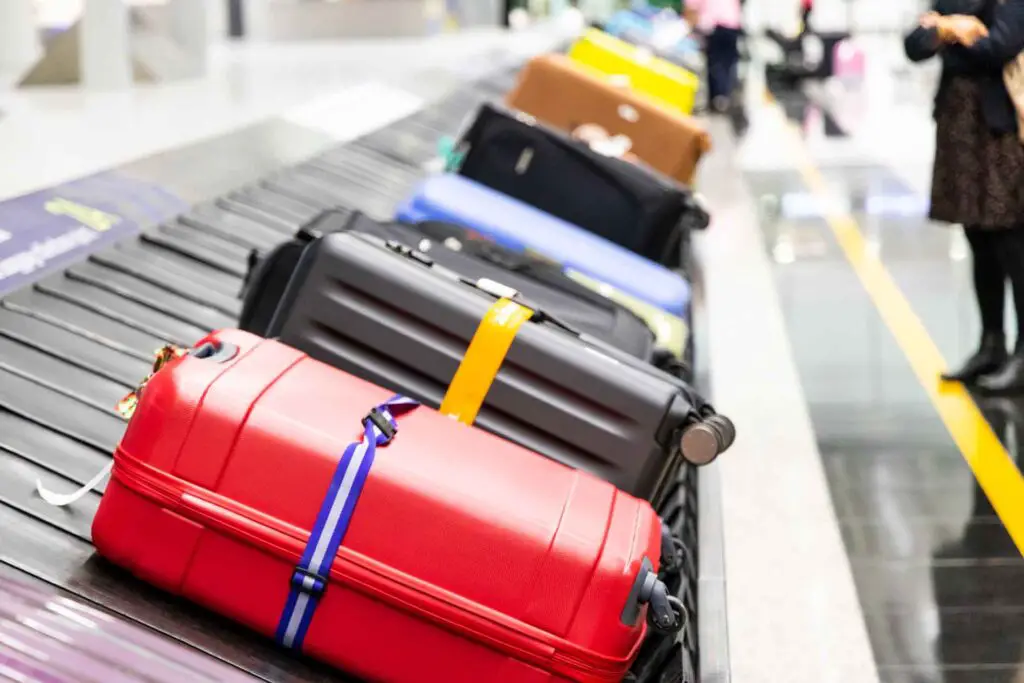 Luggage on baggage carousel wrapped with brightly colored straps.