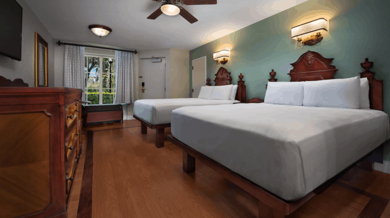 Interior shot of Disney World Port Orleans French Quarter room with 2 queen beds with white cover.