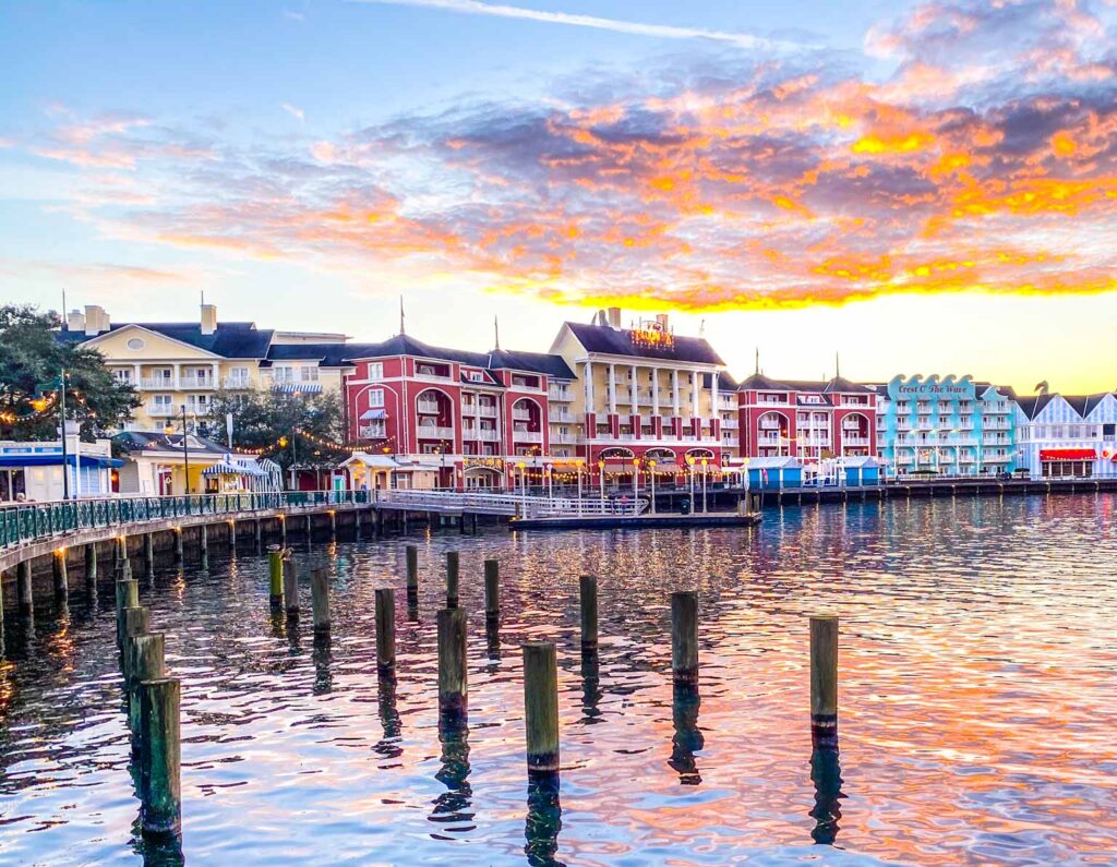 red and pastel colored historic buildings line the boardwalk in front of a lake at Disney's Boardwalk Inn near EPCOT