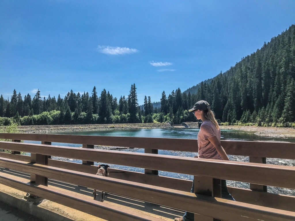 Young woman and dog walk the bridge over the McKenzie River at Carmen Reservoir, south of Koosah Falls in Oregon