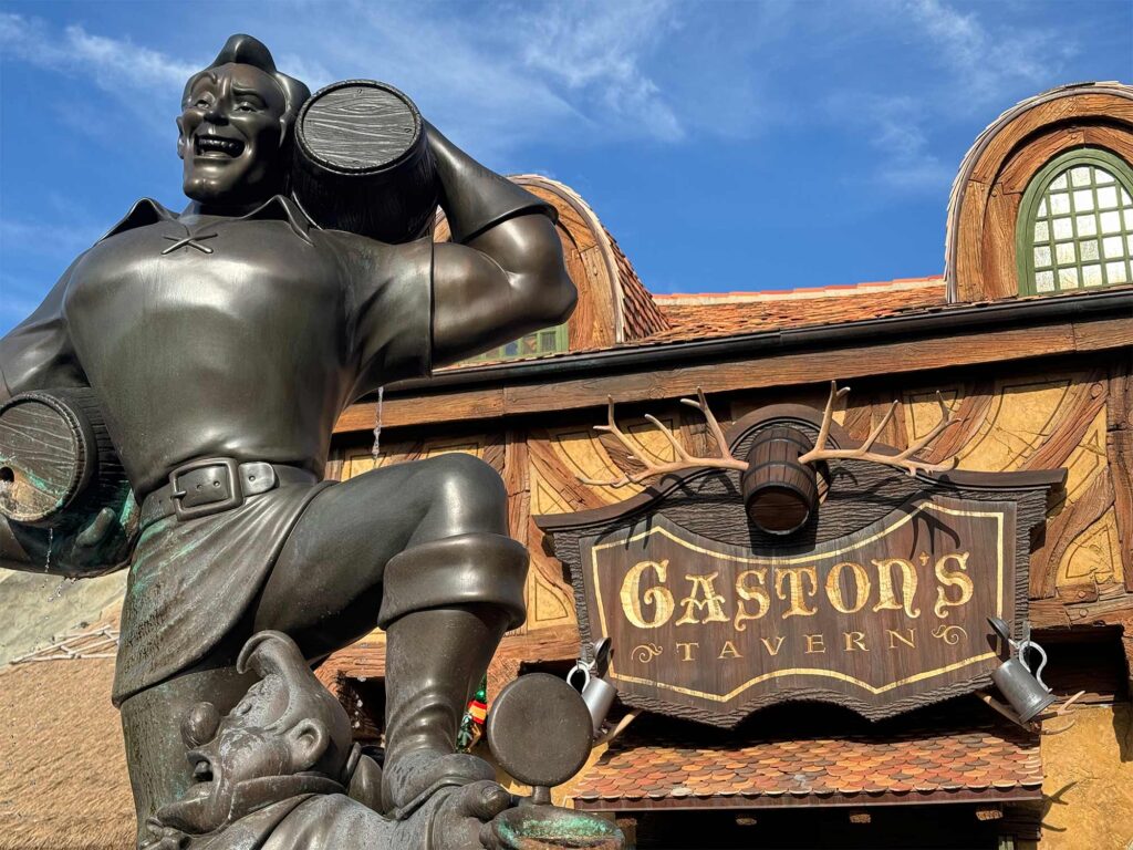 Large statue of Gaston hefting a barrel outside a French lodge inspired building bearing the name Gaston's