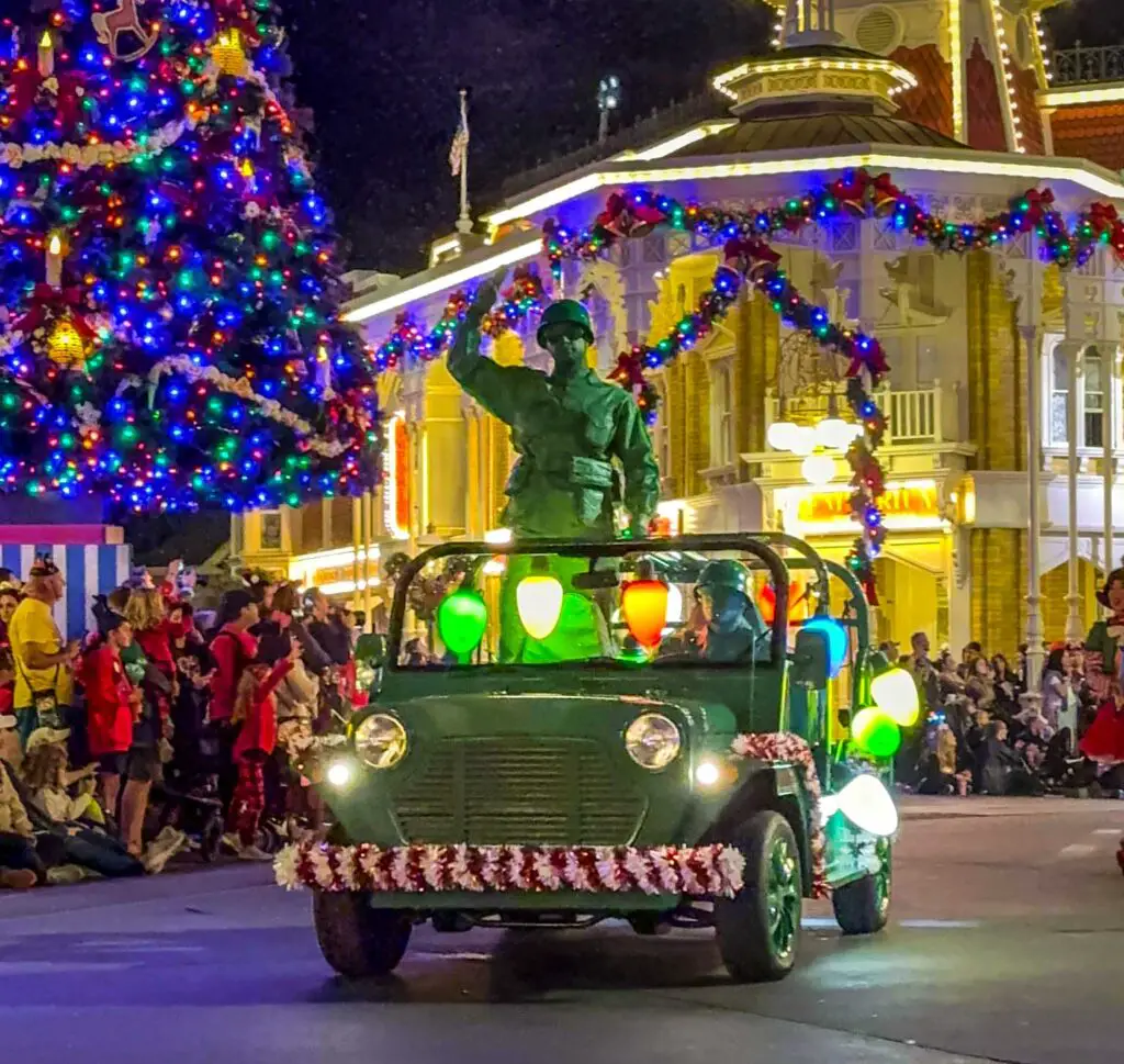 Parade at Mickey's Very Merry Christmas Party, featuring a green army man in green arm jeep in front of the Magic Kingdom Christmas tree.