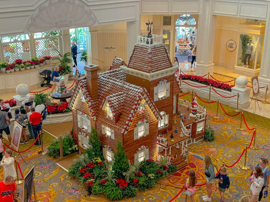 Giant gingerbread house decked in white icing trim in hotel lobby.